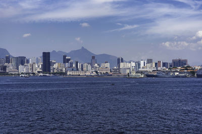 Sea by buildings against sky in city