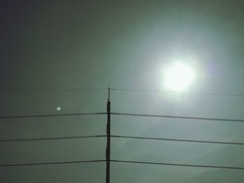 Low angle view of electricity pylon against sky on sunny day