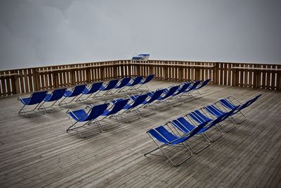 Empty chairs on floor against blue sky