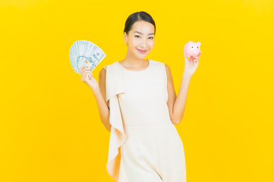 Portrait of a smiling young woman against yellow background