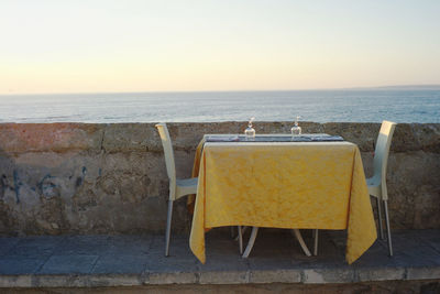 Chairs and tables on beach against clear sky