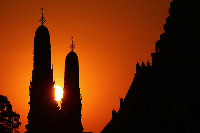 Sun setting among the silhouette of wat arun temple 's two of four smaller spires, bangkok, thailand