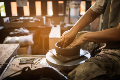 Midsection of potter making pottery at workshop