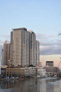 Buildings by river against clear sky