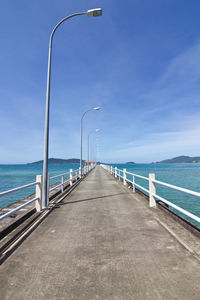 View of street leading towards sea against blue sky