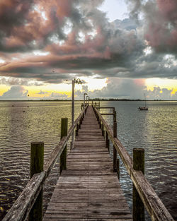 Pier over sea against sky during sunrise