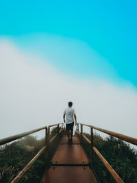 Rear view of man standing on footbridge