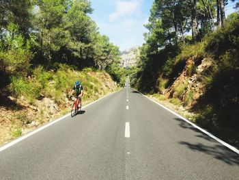 Cyclist riding on road during sunny day