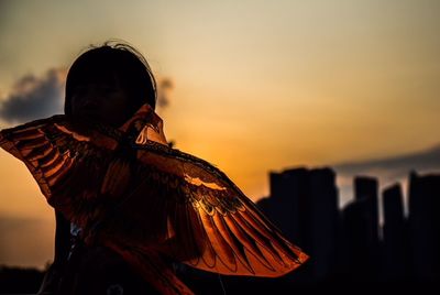 Woman with umbrella against sky during sunset