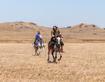 People riding motorcycle on field against clear sky