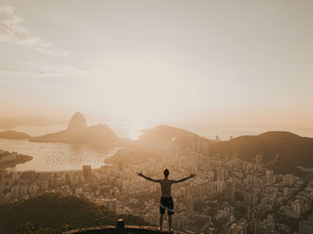 Rear view of man standing on mountain against sky