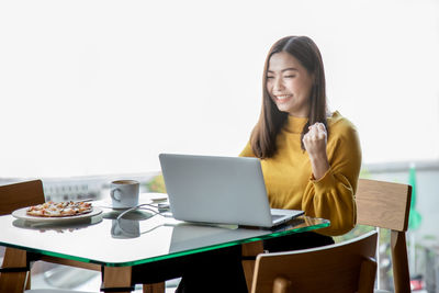 Young woman using phone while sitting on table