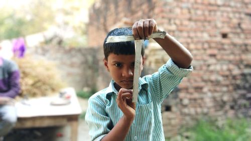 Portrait of boy holding old plastic while standing in village