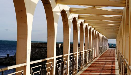 Elevated walkway by sea on sunny day