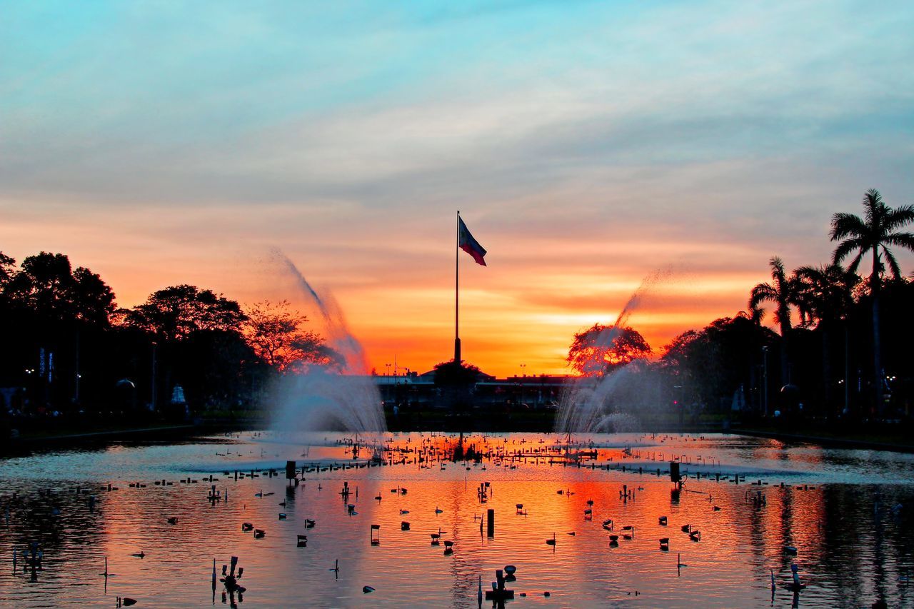 water, sunset, bird, sky, reflection, orange color, cloud - sky, tree, flying, animals in the wild, waterfront, animal themes, wildlife, lake, silhouette, cloud, beauty in nature, nature, scenics, built structure