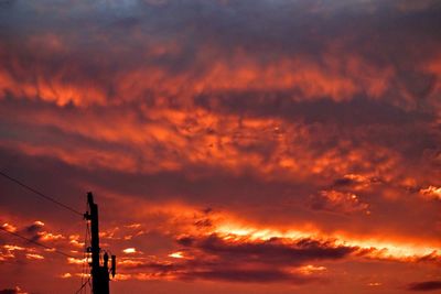Silhouette communications tower against sky during sunset
