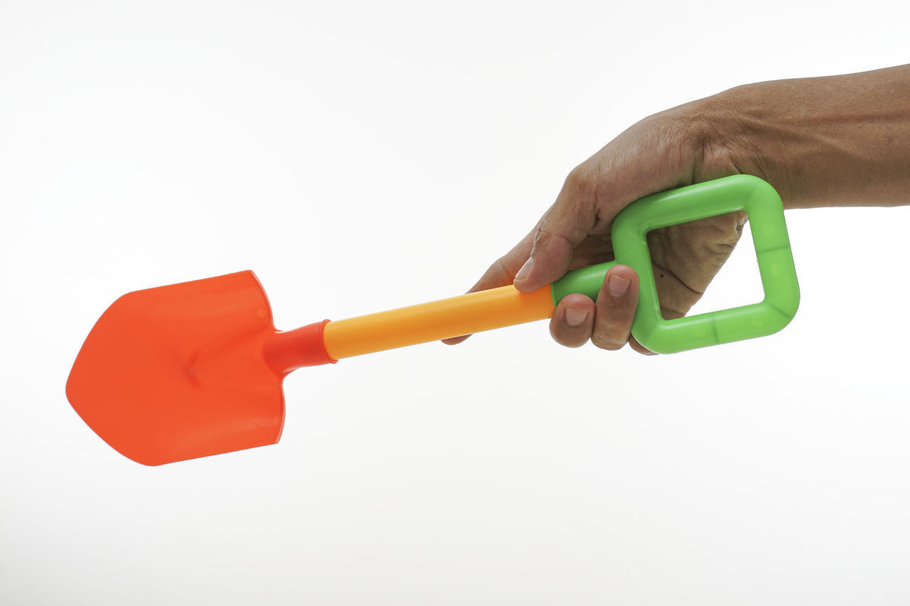 CLOSE-UP OF A HAND HOLDING TOY OVER WHITE BACKGROUND