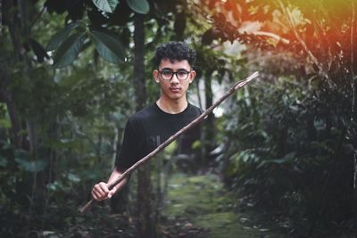 Portrait of young man holding plant in forest