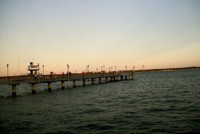 Pier in sea at sunset