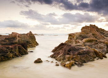 Rock formation on sea against sky during sunset