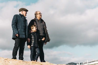 Full length of senior men with child standing against sky