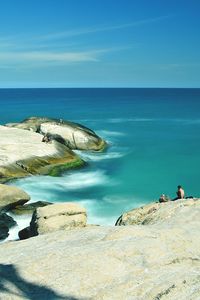 Scenic view of rocky shore against blue sky