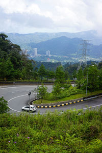 Road by trees against sky in city