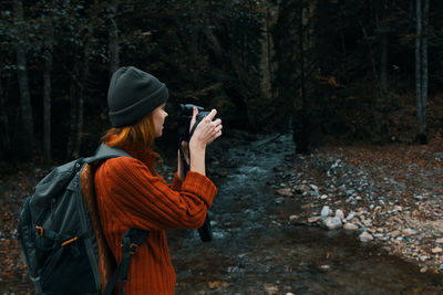 Man photographing with mobile phone in forest