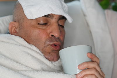 Man suffering from headache having coffee on bed at home