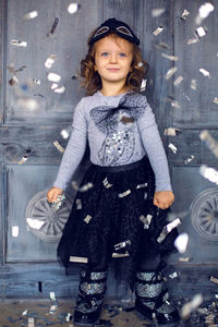Portrait of a little girl 2 years. studio in a black mask and a big bow and falling silver confetti