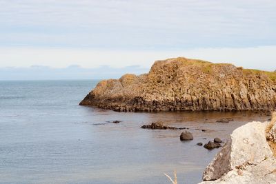 Rock formations by sea against sky