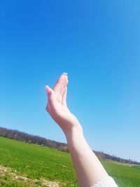 Midsection of person on grassy field against clear sky
