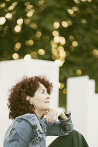 Woman in a denim jacket with a thoughtful attitude in a park