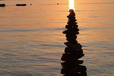 Silhouette stack of rocks against sea during sunset