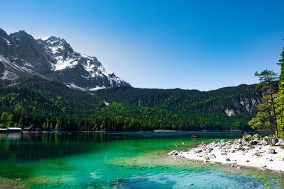 Scenic view of lake and mountains against clear blue sky
