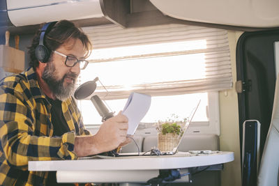 Mature man podcasting through microphone in bus