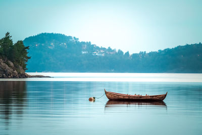 Boat floating on lake against sky