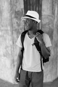 Young man wearing hat looking away while standing outdoors