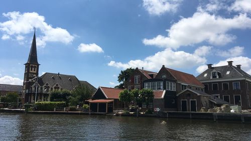 Houses by river in finland and buildings against sky