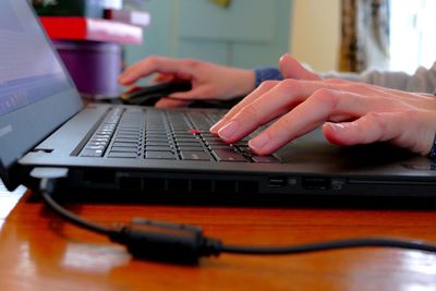 Cropped hands using laptop at table