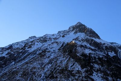 Low angle view of snowcapped mountain against clear sky