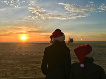 People wearing santa hat at beach against sky