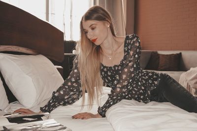 Young woman sitting on bed in bedroom