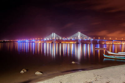 Illuminated suspension bridge over river at night