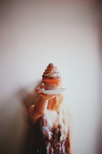 Close-up of hand holding ice cream against sky