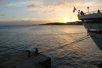 Silhouette people standing by sea against sky during sunset