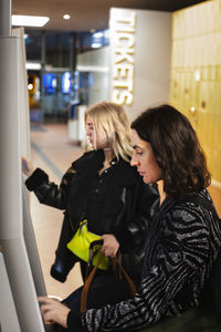 Women buying tickets in ticket machine