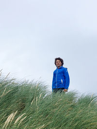 Rear view of teenager standing against sky