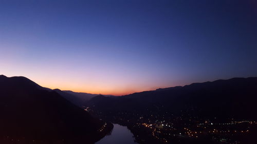 Scenic view of illuminated mountains against sky at sunset