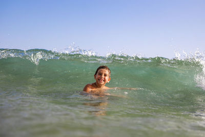 Funny kid playing with waves on the beach